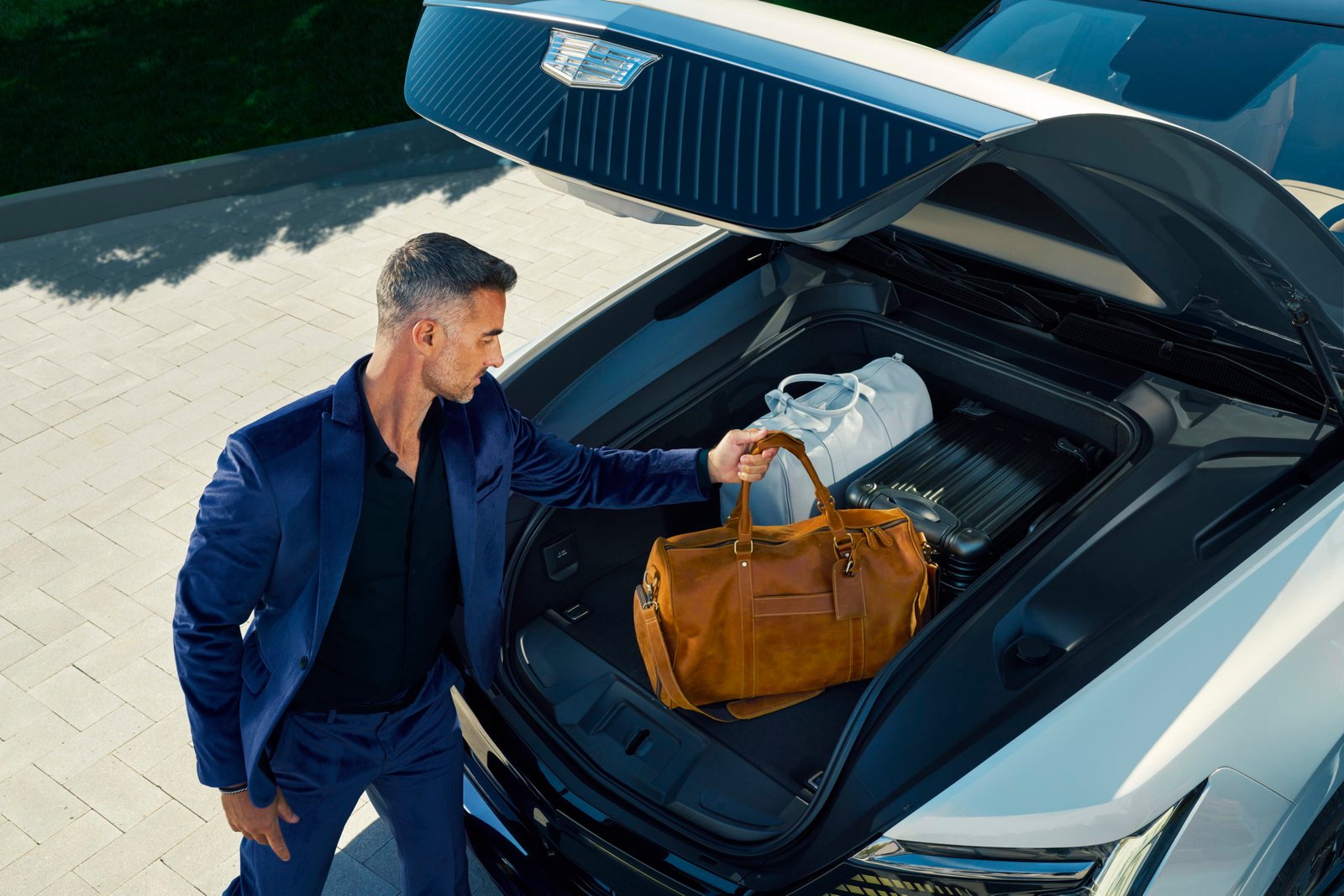 Man placing three pieces of carry-on luggage in Cadillac ESCALADE IQ eTrunk.